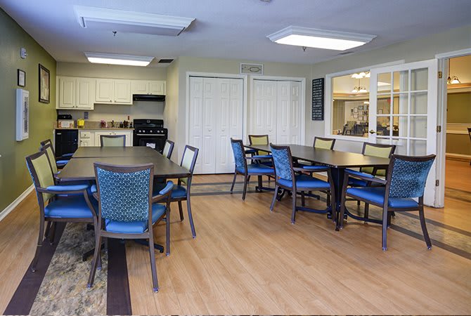 A modern dining area with tables and chairs, adjacent to a kitchen.