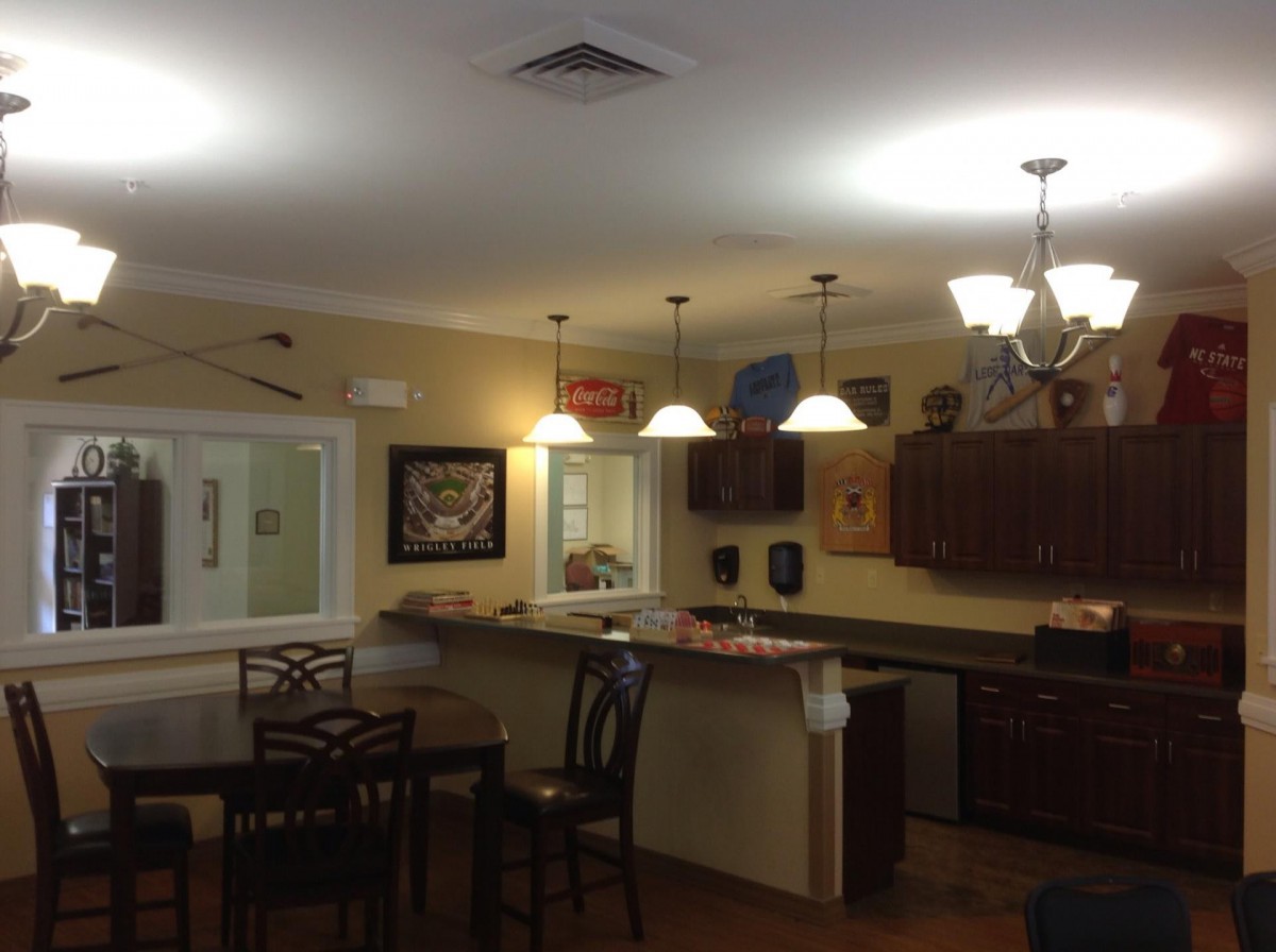 A cozy kitchen and dining area with a bar counter, wooden cabinets, and various lighting fixtures.