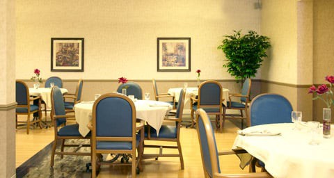 An indoor dining area with tables and chairs, decorated with wall art and plants.