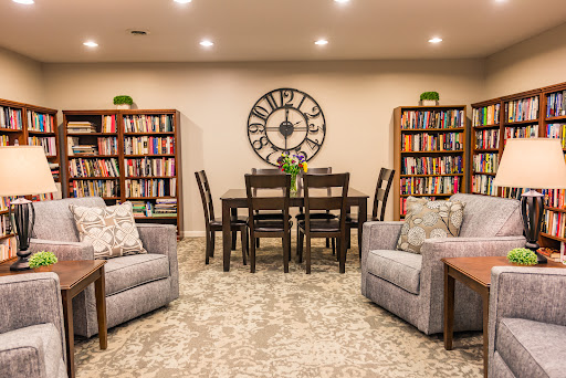 A cozy and modern living space featuring a dining area, bookshelves filled with books, and comfortable seating.
