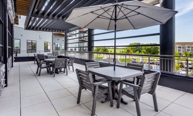 A modern patio with outdoor seating, featuring tables, chairs, and umbrellas.