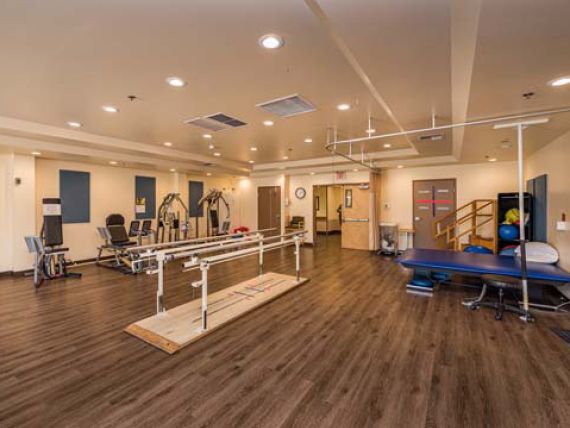 A spacious therapy center equipped with exercise machines and rehabilitation tools.
