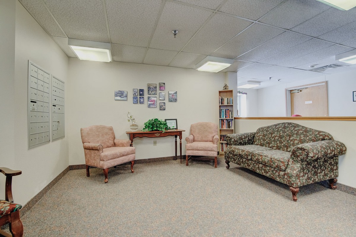 A cozy waiting room with chairs and a sofa arranged around a small table, featuring simple decor on the walls.