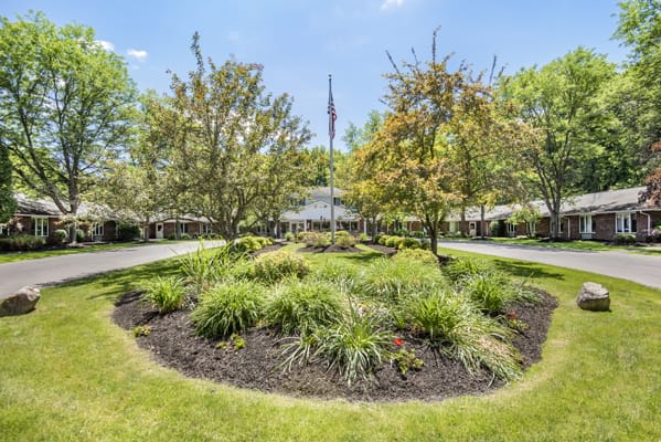 A landscaped garden with a flagpole in the center of a roundabout.