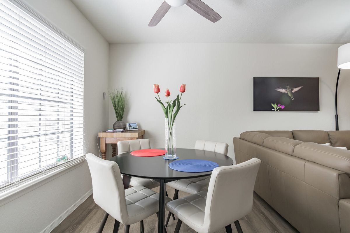 A modern, minimalist dining area with a round table and chairs, decorated with tulips in a vase.