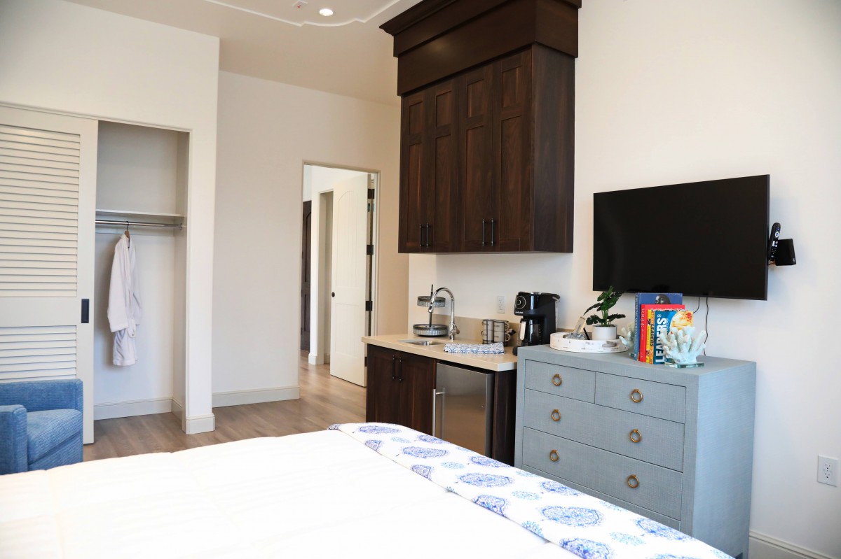 A modern bedroom featuring a TV, coffee maker, and dresser.