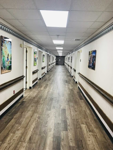 A long, well-lit hallway adorned with various pieces of artwork on the walls.