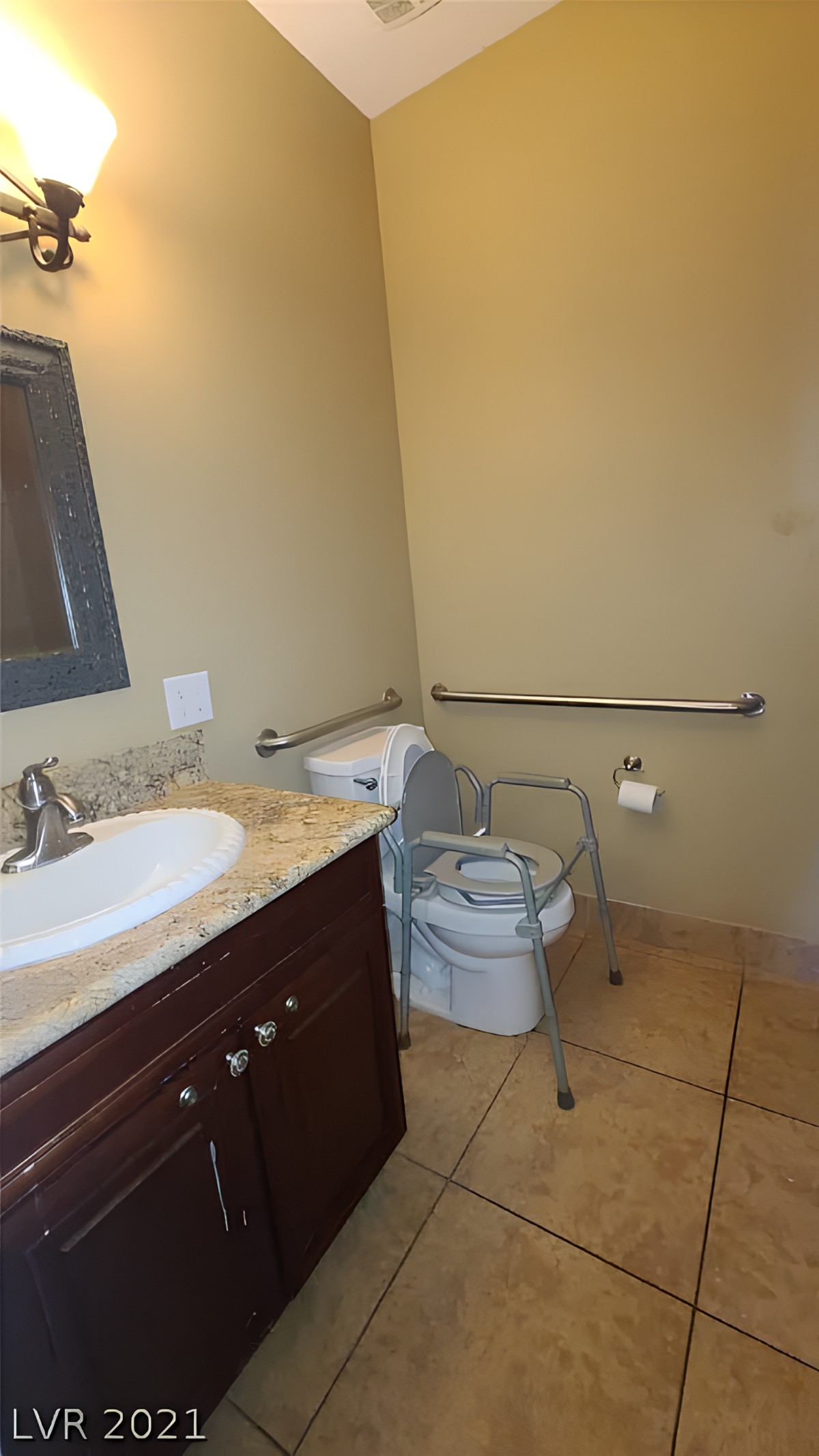 An accessible bathroom with a sink, toilet, and handrails.