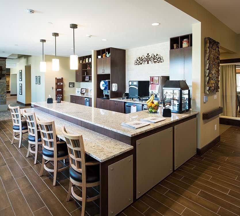 A modern kitchen with a large island, bar stools, and stylish pendant lighting.