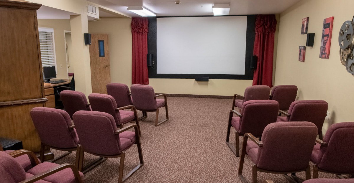 A small, cozy projection room with chairs facing a large screen.