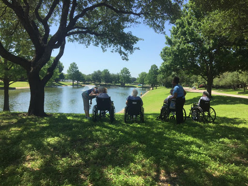 Elderly individuals enjoying a serene day by the lake in a park.
