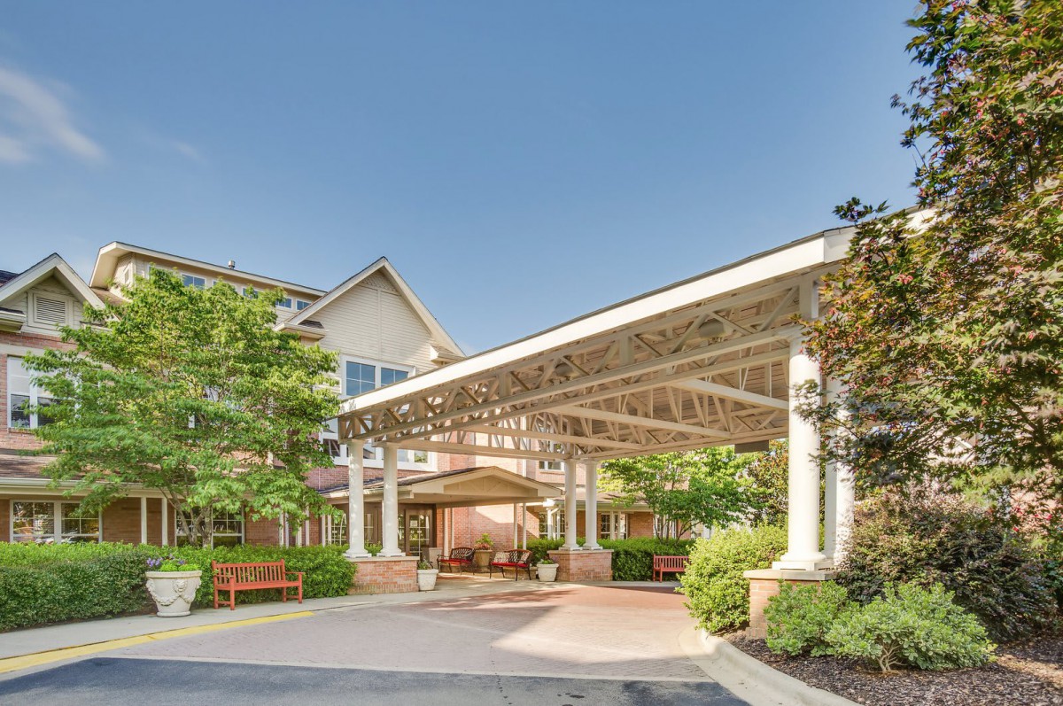A welcoming building entrance with a spacious canopy and landscaped gardens.