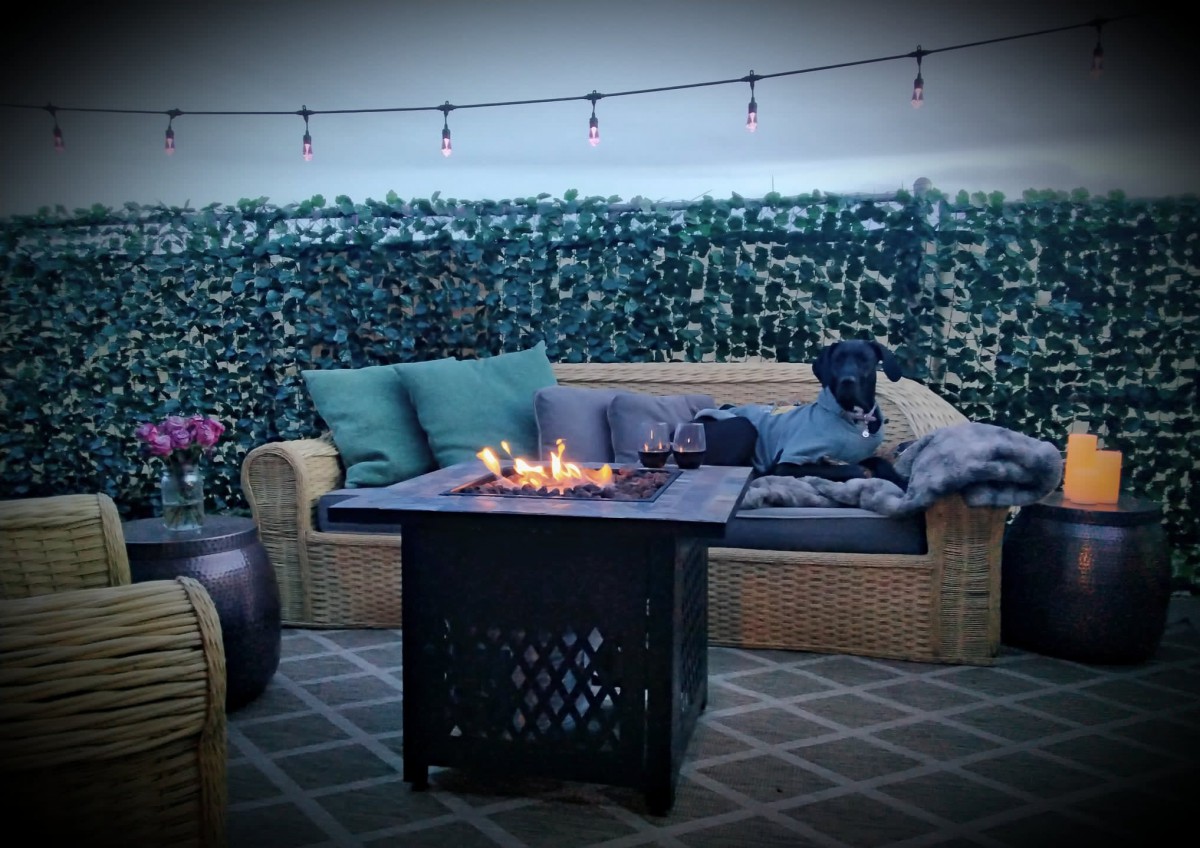 Cozy outdoor patio with a fire pit, wicker seating, and string lights, perfect for relaxing evenings.