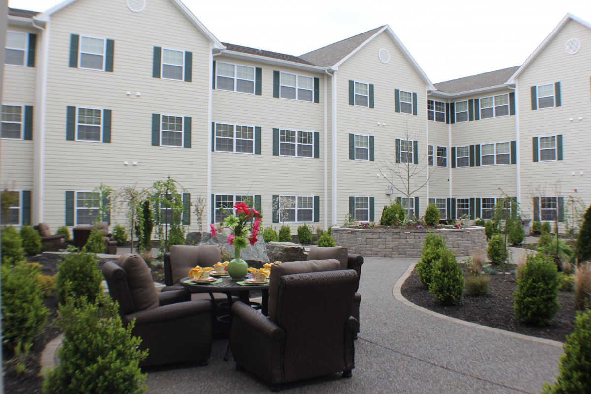 A residential building with outdoor seating and landscaped greenery.