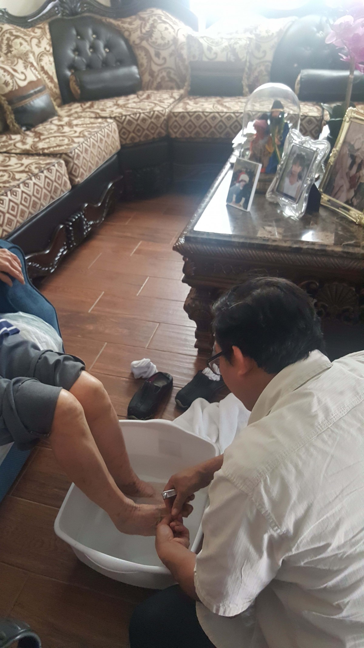 A person is seated while another person provides foot care in a home setting.