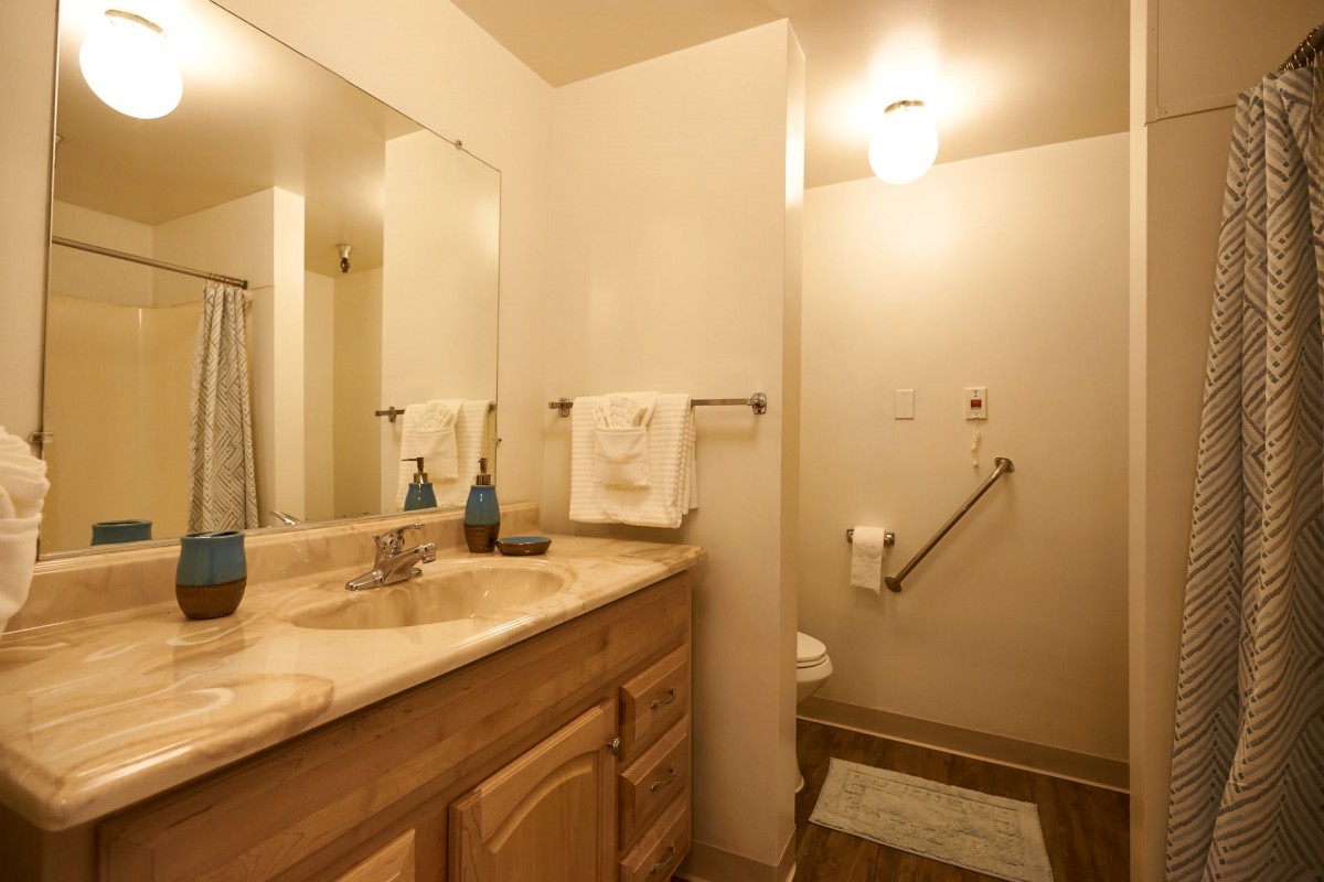 A well-lit bathroom with a sink, mirror, and shower area.