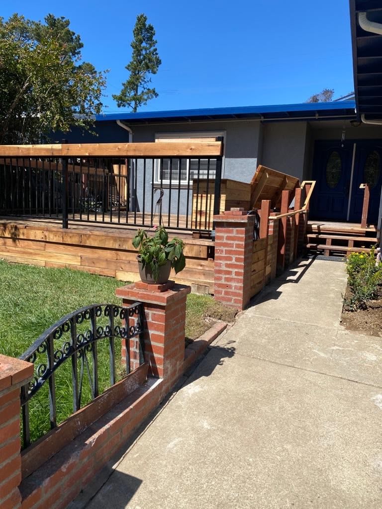 A house with a wooden deck, surrounded by a garden and brick fence.
