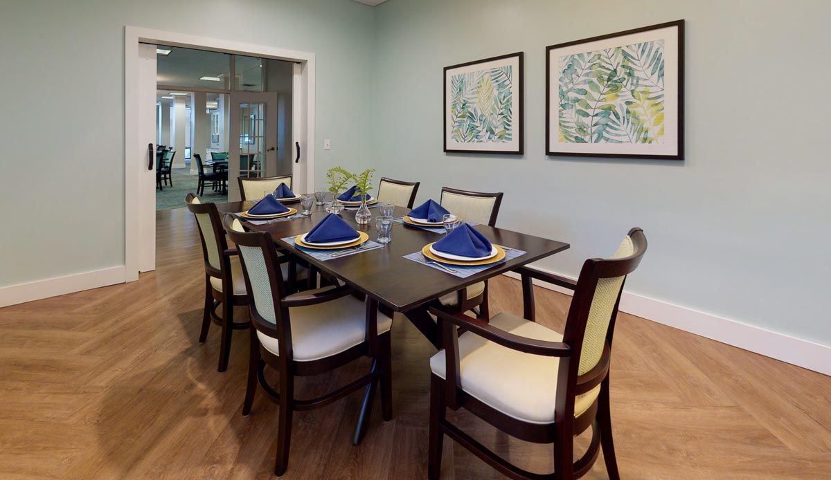 A neatly arranged dining room with a dark wooden table, complemented by upholstered chairs and vibrant blue napkins.