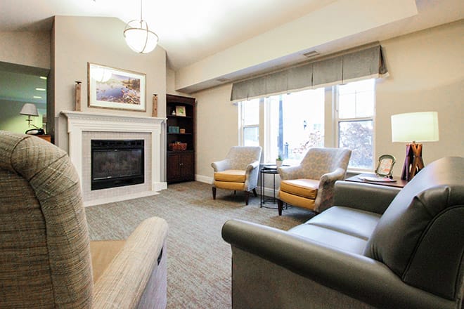 A cozy living room with a fireplace, seating area, and large windows.