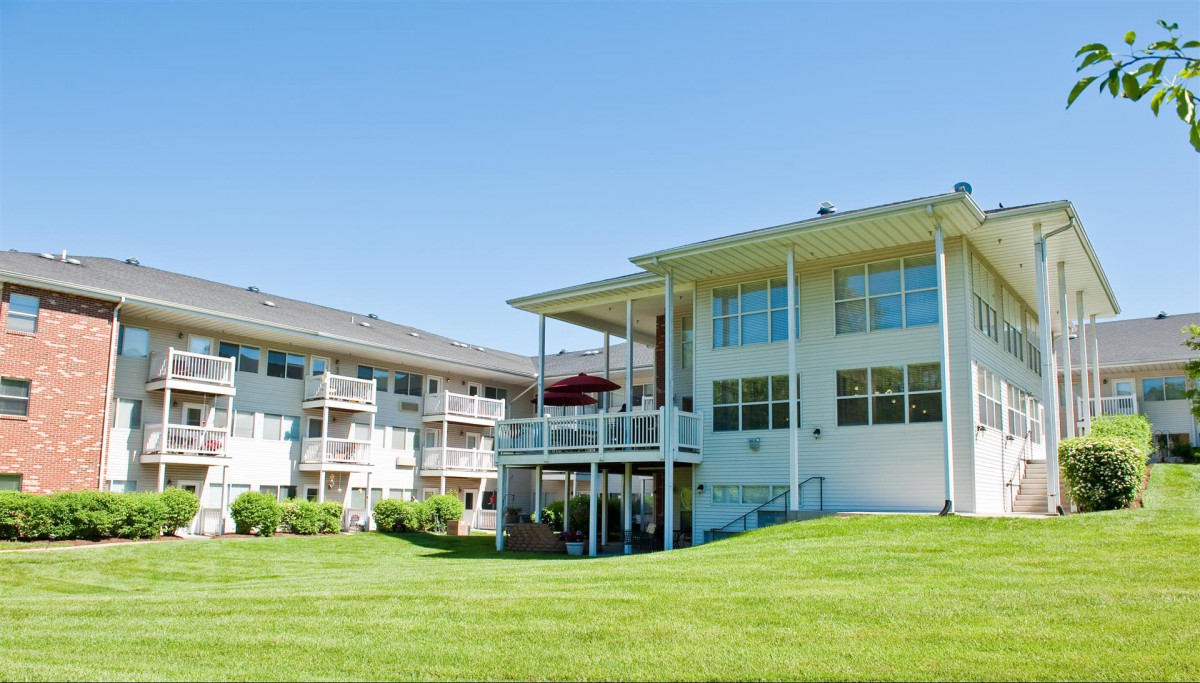 A residential apartment complex with well-maintained lawns and balconies on a sunny day.