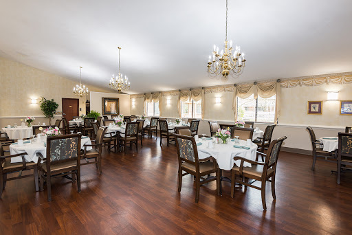 A spacious and elegantly decorated dining room featuring wooden furniture and chandeliers.