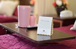 A welcoming setup with a sign and pink decor items in a cozy hotel room.