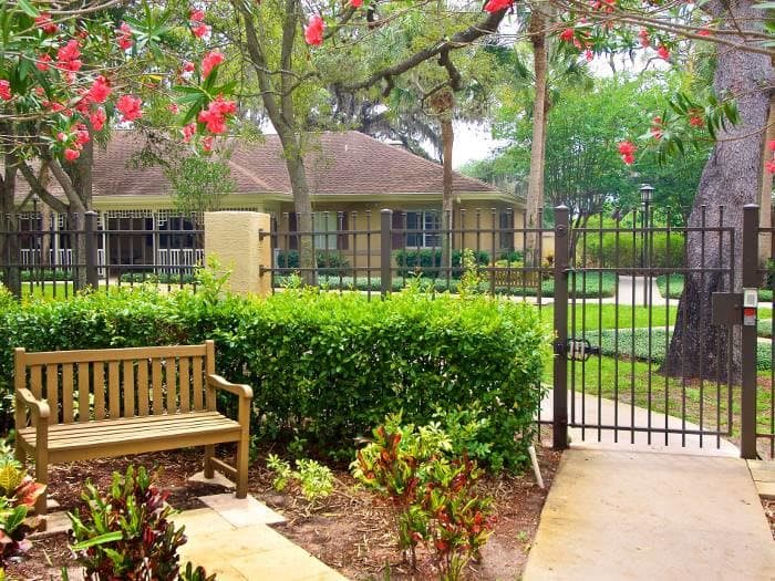 A serene garden with a bench, gate, and vibrant flowers.