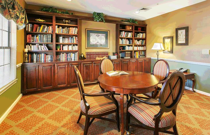 A cozy reading room with wooden furniture and bookshelves filled with books.