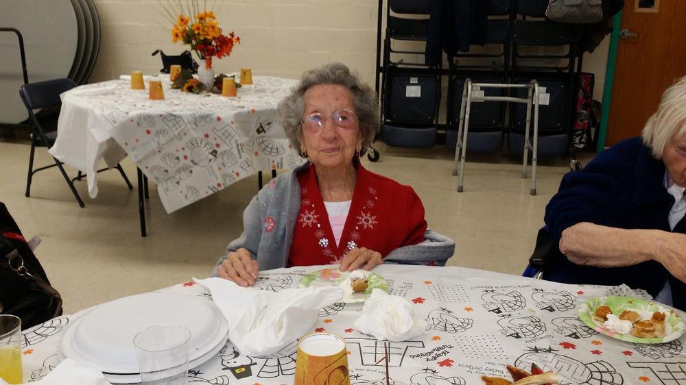 An elderly person sitting at a decorated dining table.