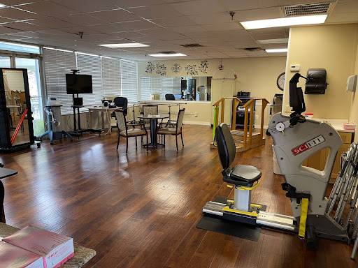 A spacious and well-equipped rehabilitation gym featuring exercise machines and a comfortable seating area.
