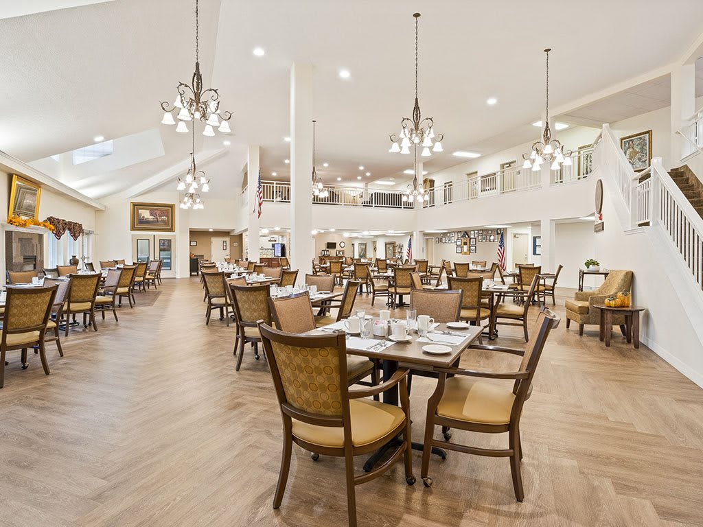An elegant dining room interior with neatly arranged tables and chairs under stylish chandeliers.