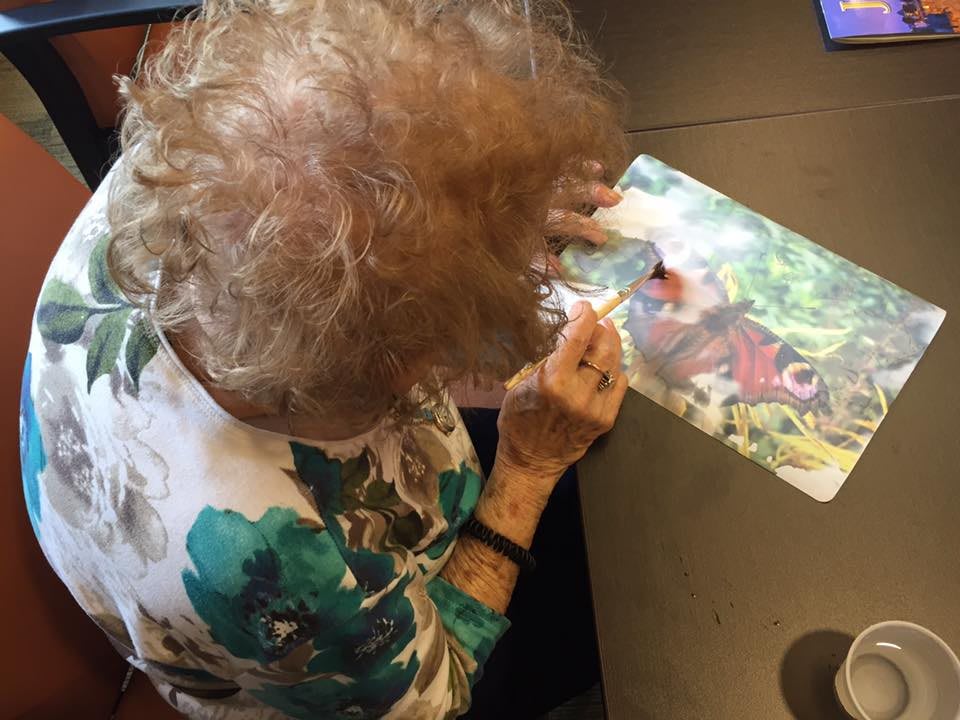 An elderly person engaged in painting a colorful artwork.