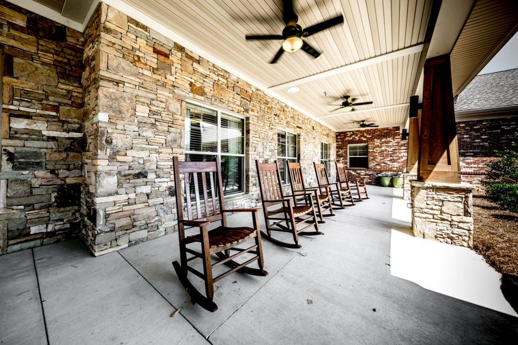 A welcoming porch lined with wooden rocking chairs and sheltered by a stone wall.