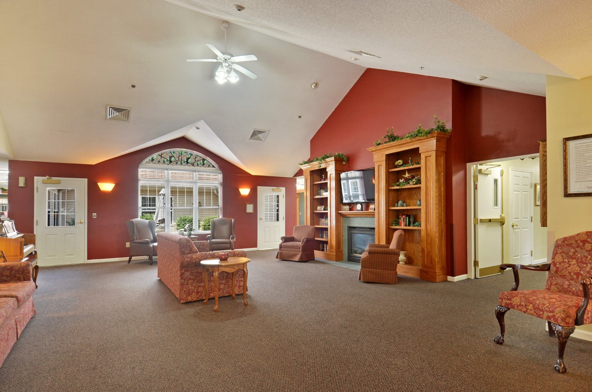 A spacious living room with high ceilings, featuring comfortable seating, bookshelves, and a fireplace.