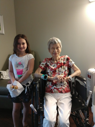 A heartwarming moment between a young girl and her elderly companion in a hospital setting.