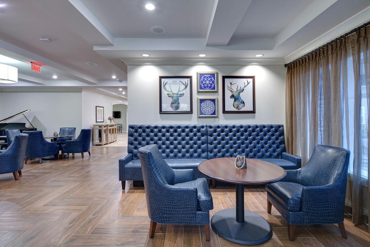 A modern lounge with blue tufted seating and decorative artwork on the walls.