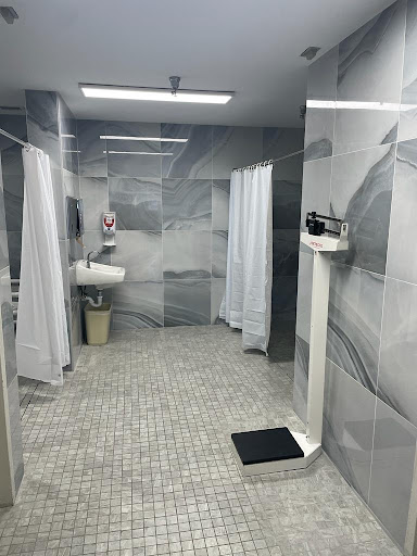 A modern bathroom featuring separate shower stalls with white curtains and a minimalist aesthetic.