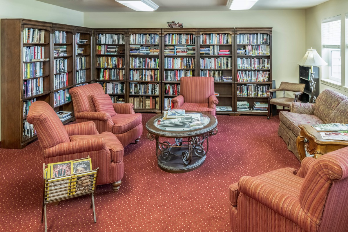 A cozy library reading room with comfortable chairs and shelves filled with books.
