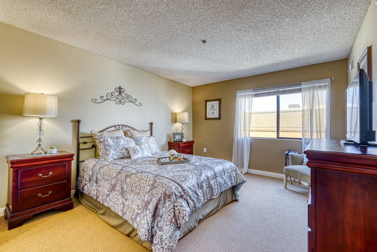 A cozy bedroom with elegant decor, featuring a stylish bed and ample natural light.