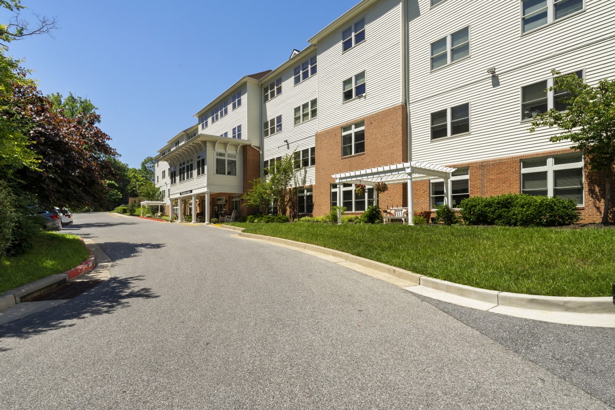 A multi-story residential building with a landscaped exterior and an adjacent road.