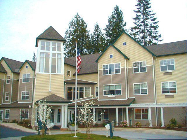A multi-story residential building with a flagpole and surrounding trees.