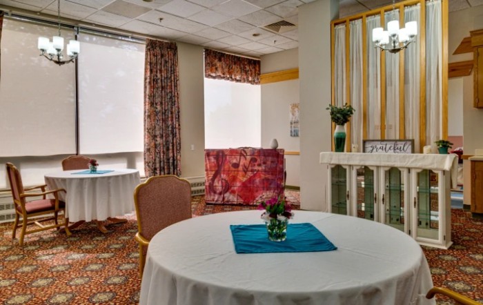 A cozy, decorated room with a table and chair by the window.