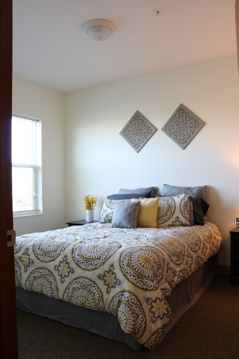 A cozy bedroom with patterned bedding, decorative pillows, and wall art.