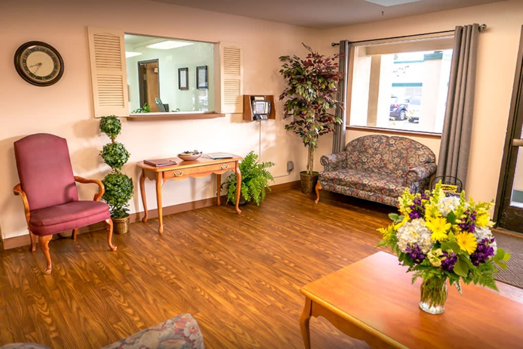 A cozy waiting area with comfortable seating, floral decorations, and a warm wooden floor.