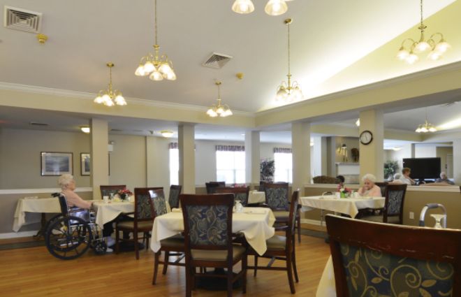 An indoor dining area with multiple tables and chairs, featuring overhead lighting.