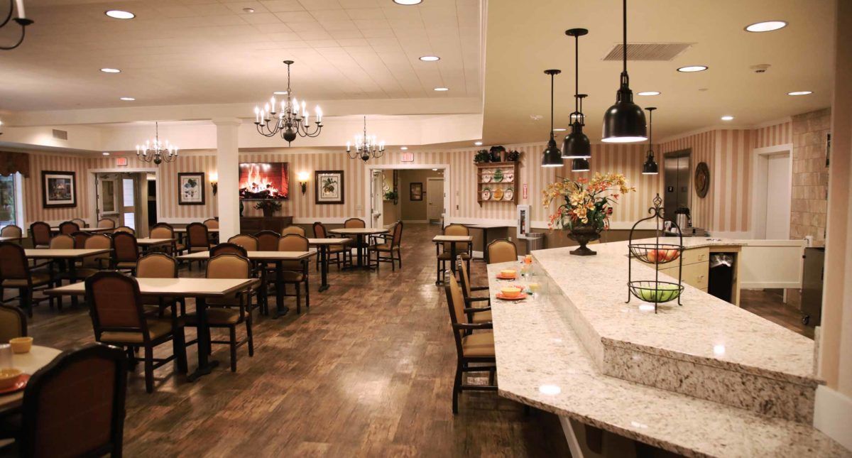 Cozy restaurant interior with a mix of dining tables, chairs, and a counter under warm lighting.