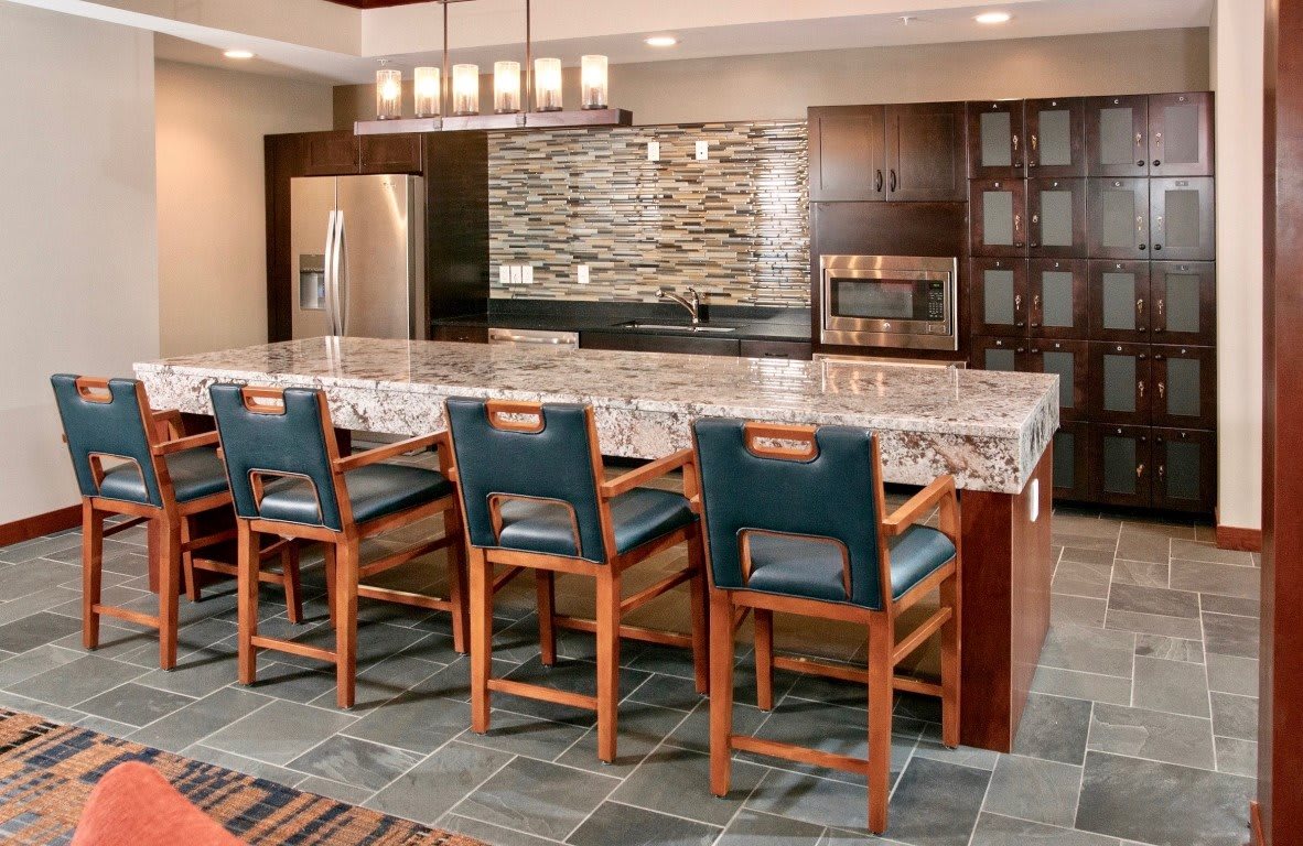 A modern kitchen with a large granite island and stylish bar stools.
