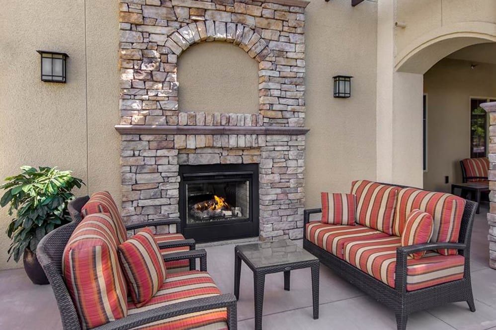 An inviting outdoor patio with comfortable seating and a cozy stone fireplace.