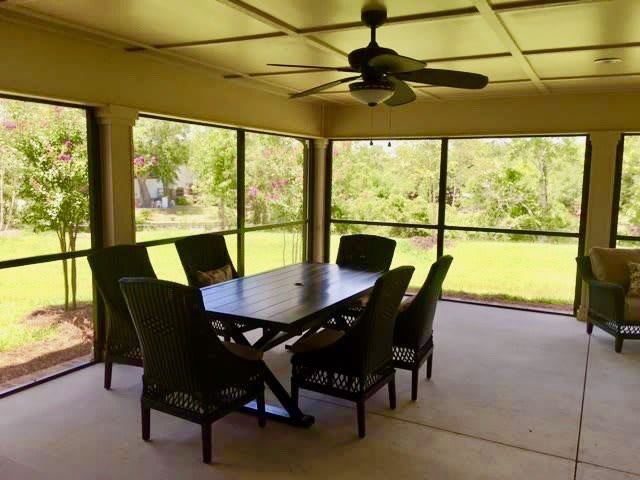 A cozy outdoor patio with a dining table and chairs, enclosed with screens offering a serene view of nature.
