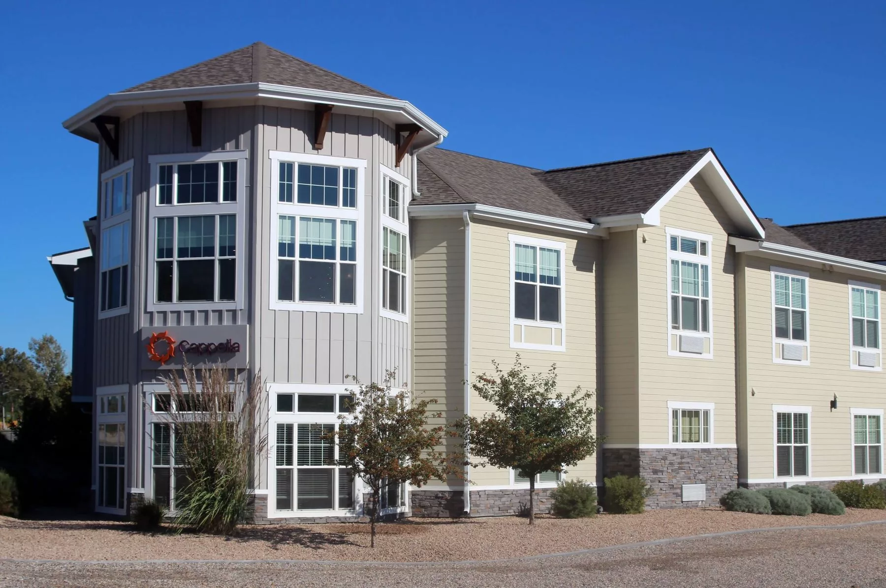 A two-story residential building with large windows against a clear blue sky.